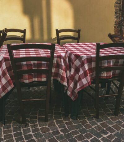Cozy outdoor café setting with red checkered tablecloths in a rustic atmosphere. Ideal for dining concepts.