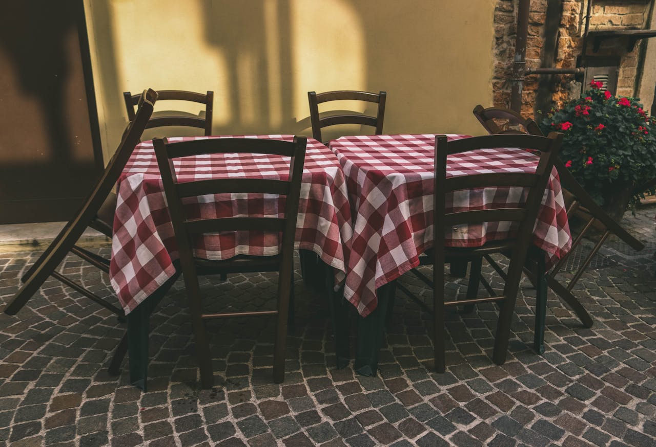 Cozy outdoor café setting with red checkered tablecloths in a rustic atmosphere. Ideal for dining concepts.